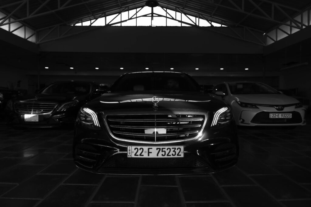 pexels-photo-28380943-28380943 Black and white image of luxury cars in a showroom, featuring a prominent front view.