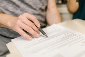 pexels-photo-7841833-7841833 Close-up of a person's hand signing an important legal document with a pen indoors.